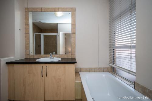乌姆德洛蒂5A Sugar Beach with Inverter的带浴缸、水槽和镜子的浴室