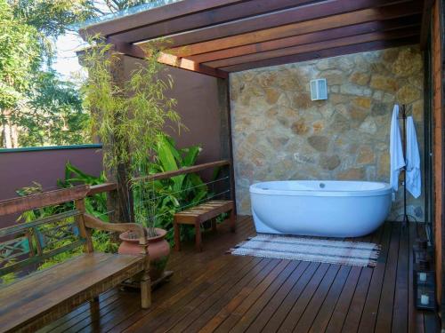 蒂拉登特斯Lofts Villa da Serra的带浴缸的浴室,位于带长凳的甲板上