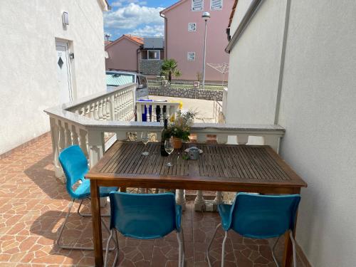 奥米沙利Apartments Michael & Petra , Omisalj, Insel Krk, Kroatien的阳台的一张木桌,配有蓝色的椅子