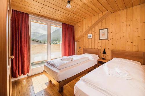 奥蒂塞伊Aquila Dolomites Residence的一间卧室设有两张床和大窗户