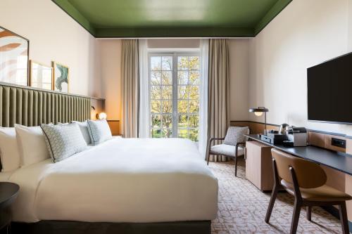 布洛涅-比扬古Le Parchamp, a Tribute Portfolio Hotel, Paris Boulogne的酒店客房设有一张大床和一张书桌。