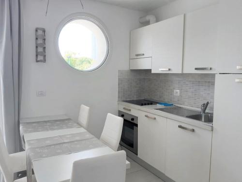 利尼亚诺萨比亚多罗假日公寓式酒店的厨房配有白色橱柜和桌椅