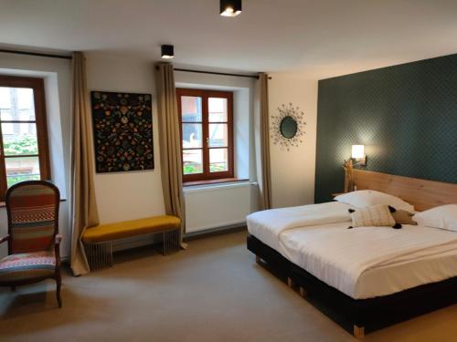 利克维圣尼古拉斯酒店的一间卧室配有一张床和一把椅子,还有两个窗户
