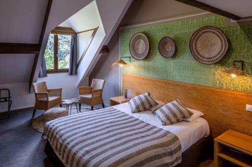 米尼亚卢博瓦尔Garrigae Manoir de Beauvoir Poitiers Sud - Hotel & Spa的酒店客房的墙上设有一张床和两个盘子