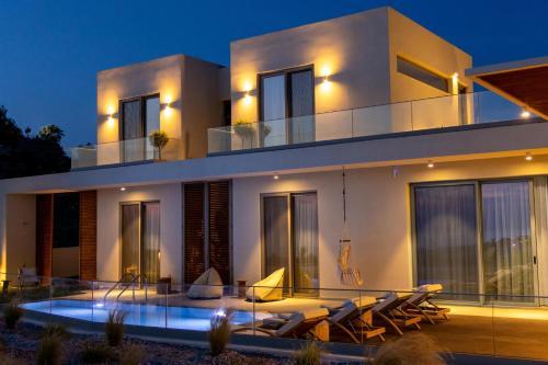 帕诺尔莫斯雷斯蒙Sueno Villas的一座白色的大房子,晚上设有游泳池