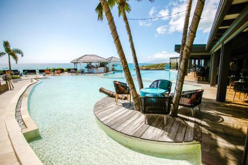 圣安尼图巴纳Spa酒店的一个带椅子和桌子的游泳池,毗邻大海