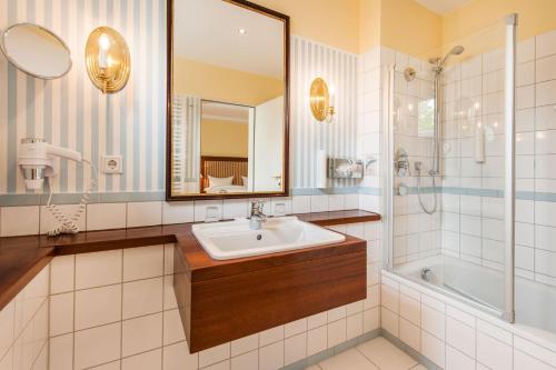 基尔Hotel Birke, Ringhotel Kiel的一间带水槽、淋浴和镜子的浴室