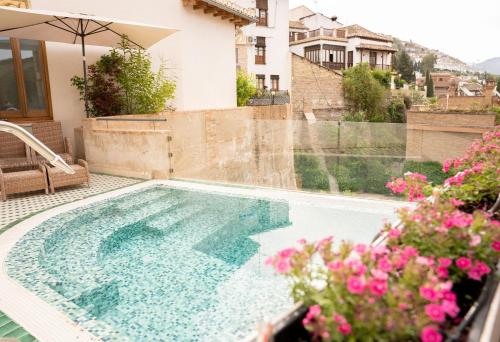 格拉纳达La Corrala del Realejo的鲜花屋前的游泳池