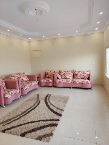 艾卜哈استراحة في منطقة مرتفعة بالقرب من أبها的客厅配有粉红色的沙发和地毯。