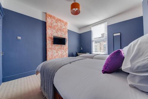 利物浦Air Host and Stay - Rockfield Lodge, sleep 12 free parking next to LFC的一间卧室设有蓝色的墙壁和一张带紫色枕头的床