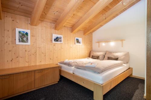 GadmenTälli Hütte的卧室配有木墙内的一张床