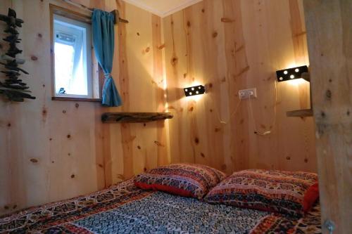 登堡Tiny home Texel的卧室配有一张床铺,位于带木墙的房间内