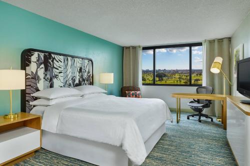 迈阿密喜来登迈阿密机场酒店及行政会议中心的一间卧室配有一张床、一张书桌和一台电视