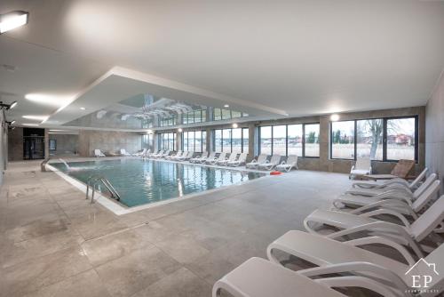 济夫努夫Apartament RiverView Bridge Apartments & Spa Dziwnów Epapartamenty的一座带白色椅子的大型游泳池