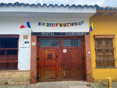 卡利HOSTAL CHONTADURO Casa colonial en pleno centro histórico de Cali- Se alquila la casa entera para 12 o 13 personas o por habitaciones的两扇木门的房子,上面有标志