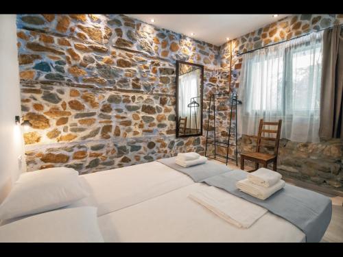 普利瑙港湾DreamStone Residence的一间卧室设有两张床和石墙