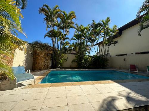 圣若泽杜斯坎普斯Casa Jardim das Colinas的棕榈树屋前的游泳池