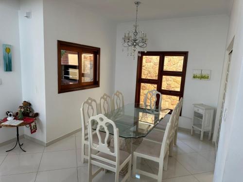 圣若泽杜斯坎普斯Casa Jardim das Colinas的一间设有玻璃桌和白色椅子的用餐室