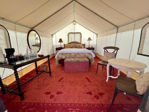 PaoniaCosmo Glamping Tent at Zenzen Gardens的一间卧室配有一张床,帐篷内配有一张桌子