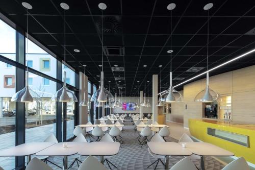 哈尔伯格摩斯prizeotel Munich-Airport的一间设有白色桌椅和窗户的自助餐厅