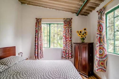 乔阿奇Finca Umnisa - Choachi的一间卧室设有一张床和两个窗户。