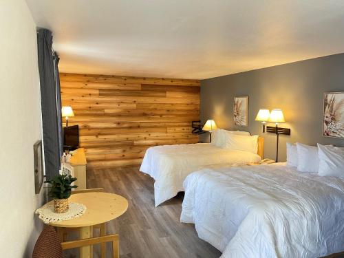 科迪Moose Creek Lodge & Suites的酒店客房设有两张床和木墙
