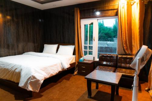锡卡都Saspolo chain of G house的一间卧室配有一张床、一张沙发和一个窗口