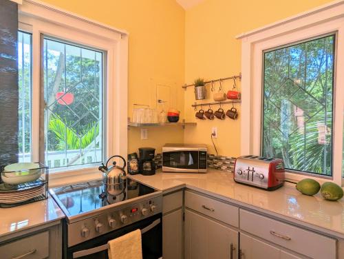 罗阿坦West Bay Roatan - Sunny & Modern Oasis- 2 Bedrooms - 3 min walk to beach的厨房配有带微波炉和水槽的台面