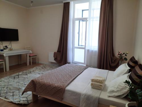 PromyshlennyyКвартира ЖК Балкадиша的一间卧室配有一张床、一张书桌和一个窗户。