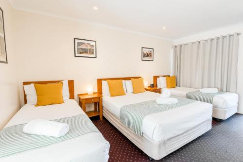 滕特菲尔德The Henry Parkes Tenterfield的酒店客房,设有3张带黄色枕头的床