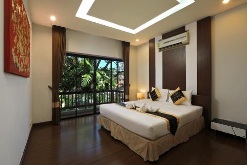 拉威海滩Rawai Grand House -SHA Plus的一间卧室设有一张大床和一个大窗户