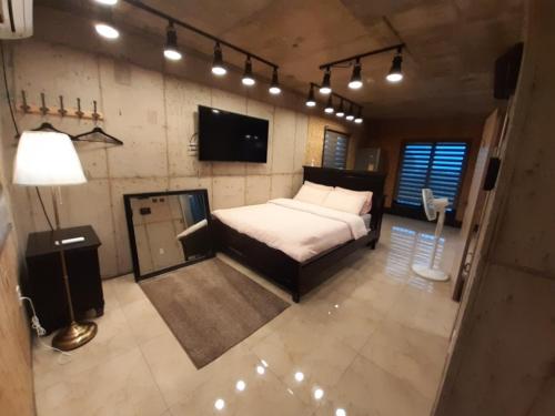 西归浦市Soo Stay的一间卧室配有一张床、一台电视和灯
