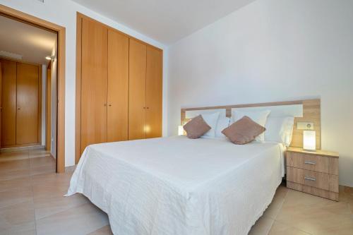 L'AldeaSara的卧室配有白色的床和木制橱柜。