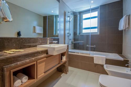 迪拜Jood Hotel Apartments的浴室配有水槽、淋浴和浴缸。