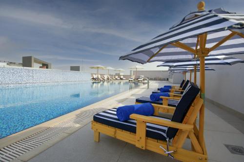 迪拜Jood Hotel Apartments的游泳池旁一排带遮阳伞的躺椅