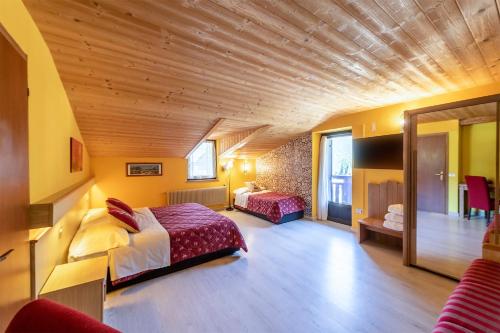 佩约方缇Hotel Alpino Wellness & Spa的一间卧室设有两张床和木制天花板
