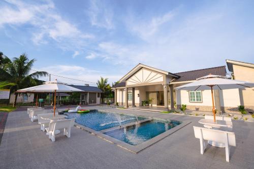 马六甲Villa Dracaena Melaka With Swimming Pool, Hill View and 20 minutes to Town的一座房子,设有一座带椅子和遮阳伞的游泳池