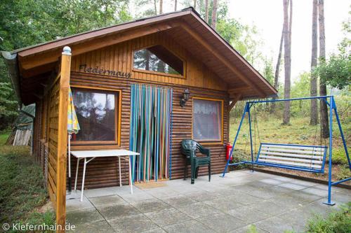 滨湖克拉科Feriensiedlung Kiefernhain的小屋设有长凳和秋千