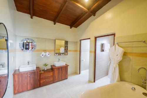 KisoroGorilla Heights Lodge的带浴缸、两个盥洗盆和淋浴的浴室。