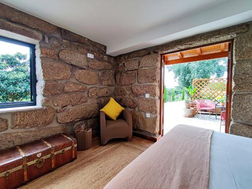 CoutoVerde Água Agroturismo e Agricultura Biológica的带石墙的客房配有一张床和一把椅子