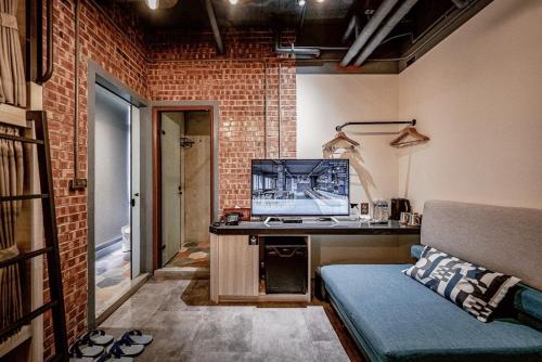 嘉义市嘉义轻行旅的客房设有一张沙发和一张带电视的书桌。