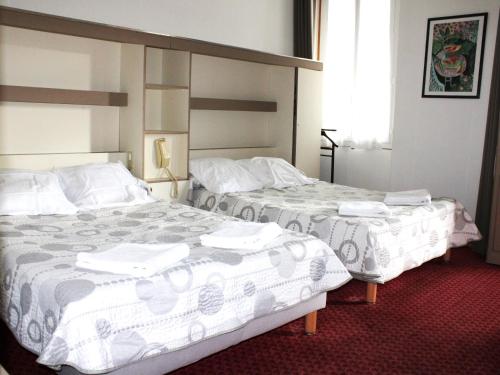 卢尔德Hotel Du Gave的配有白色床单的酒店客房内的两张床
