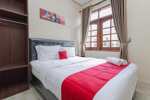 巴图RedDoorz at WR Supratman Batu的一间卧室配有一张带红色毯子的大床