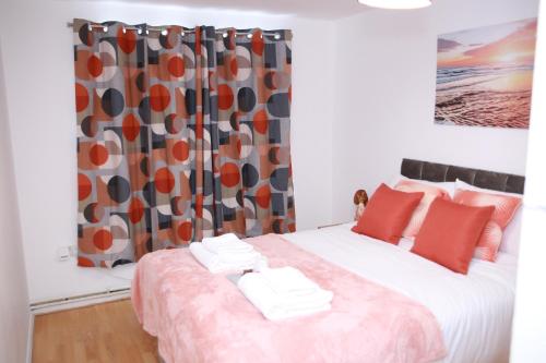 哈罗Kenton Cozy Apartment的一间卧室配有一张带红色枕头的床和窗帘