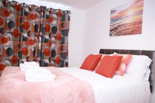 哈罗Kenton Cozy Apartment的一间卧室配有红色和橙色枕头的床