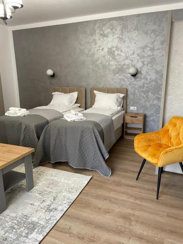 德瓦Burebista Residence的一间卧室配有两张床和椅子