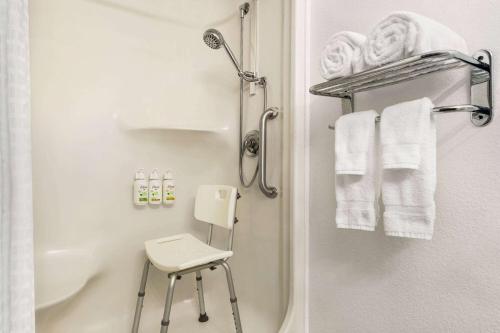 海伦娜Ramada by Wyndham Helena的带淋浴、凳子和毛巾的浴室