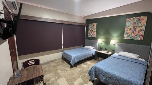 瓜亚基尔Hotel Varadero Internacional的酒店客房设有两张床和一张桌子。