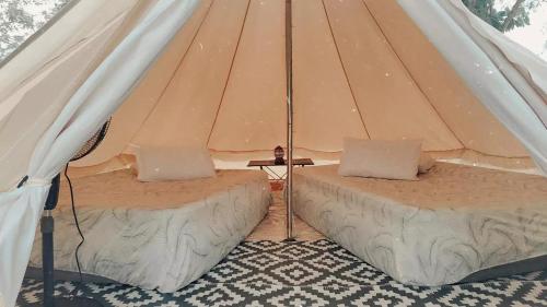 Kampong Tanjong Che LahomRustika Glamping的帆布帐篷内的两张床和一张桌子