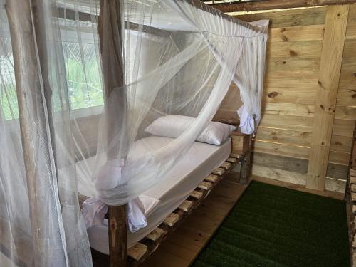 江比阿Coconuts Bandas的配有蚊帐的木制客房内的一张床位